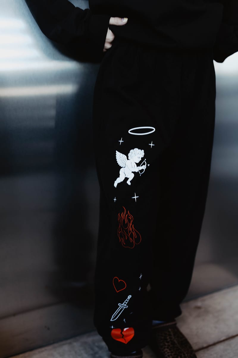 Detail of the black cherub sweatpants: a haloed cherub, red flame, heart and dagger